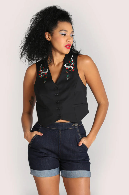 A model wearing a black semi fitted waistcoat with v-neckline and snake embroidery on the chest, and denim shorts.